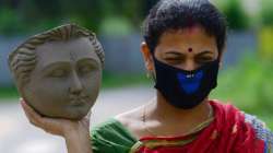 A woman artisan carries the face-idol of Goddess Durga at a studio in Agartala.