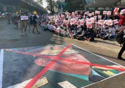 A large image that has an X mark on the face of Commander in chief Senior Gen. Min Aung Hlaing, also chairman of the State Administrative Council, lies on a road as anti-coup protesters gather outside the Hledan Centre in Yangon, Myanmar, Sunday, Feb. 14, 2021. Daily mass street demonstrations in Myanmar are on their second week, with neither protesters nor the military government they seek to unseat showing any signs of backing down from confrontations.