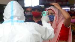 A health worker checks the temperature of a passenger at Bandra train station in Mumbai. Health officials have detected a spike in COVID-19 cases in several pockets of Maharashtra state, including in Mumbai.