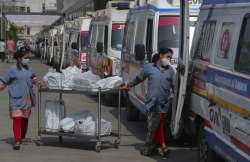 Hospital staff distribute food packets to the staff of ambulances carrying COVID-19 patients and their relatives as they queue up waiting for their turn to be attended at a government COVID-19 hospital in Ahmedabad