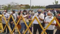 People stand behind a barrier outside a Covid-19 vaccination centre as vaccination was stopped due to shortage of vaccine supplies, in Mumbai.