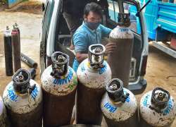 Workers sort medical oxygen cylinders meant for Covid-19 patients, before dispatching them to hospitals, amid surge in coronavirus cases, at BMTC bus stand in Bengaluru