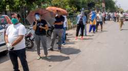 People wait in a queue to receive COVID-19 vaccine doses, outside ESI Hospital in Noida.