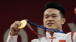 Shi Zhiyong of China celebrates on the podium after winning the gold medal in the men's 73kg weightlifting event, at the 2020 Summer Olympics, Wednesday, July 28