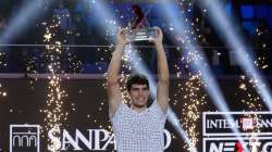 Spain's Carlos Alcaraz holds a trophy after winning the ATP Next Gen final tennis tournament against