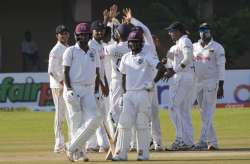 West Indies batters wait for DRS review decision while Sri Lanka players (behind) stand in a huddle in Colombo on Thursday.