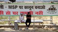 Two persons sit at a bus stop at the Ghazipur border as barricades are removed from the farmers protest site.