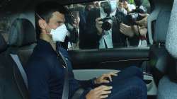 Novak Djokovic rides in a car as he leaves a government detention facility before attending a court 