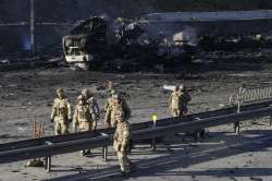 Ukrainian soldiers walk past debris of a burning military truck on a street in Kyiv, Ukraine