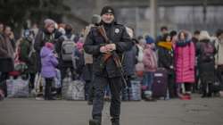 A Ukrainian policeman walks on a platform backdropped by people waiting for a Kiev bound train in Kostiantynivka, the Donetsk region, eastern Ukraine, Thursday, Feb. 24, 2022.