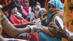 Voters holding their identification cards, wait in a queue to cast their votes for the fourth phase of UP Assembly elections, at Darbaripur polling station, in Unnao.