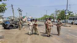 Security personnel stand beside a charred vehicle, following a communal clash during Ram Navami procession on Sunday, in Himmatnagar, Monday.