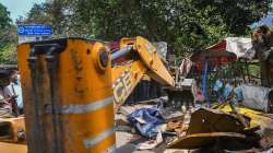 A bulldozer being used to demolish illegal structures during an anti-encroachment drive by the MCD, at New Friends Colony, in New Delhi