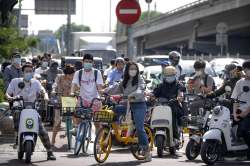 Commuters wearing face masks wait at an intersection in the central business district in Beijing, Tuesday, May 31, 2022.