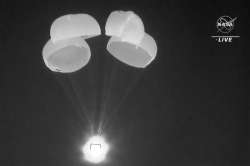 In this image made from video supplied by NASA, SpaceX Dragon capsule uses parachutes as it descends in the Gulf of Mexico.?