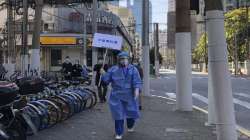 A worker in protective gear holds a sign which reads "Do not crowd" during a mass testing day for residents in a lockdown area in the Jingan district of western Shanghai