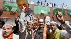 BJP supporters celebrate as early trends show the party's win in the last Uttar Pradesh and Uttarakhand assembly polls, at the party office in Lucknow.
