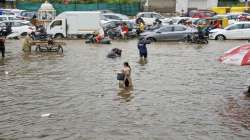 Commuters wade through a waterlogged area after heavy rainfall in Ahmedabad. 