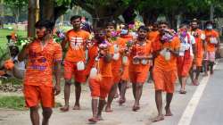 Kanwariyas carry water from the Ganga river to perform "Abhishek" at Kashi Vishwanath temple, during Sawan month, in Prayagraj. 