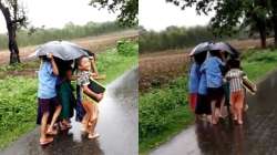 School children shelter from rain under one umbrella 