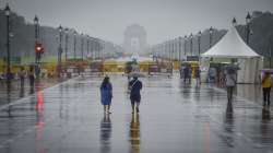 A man uses an umbrella to shield himself from rain, in New Delhi.