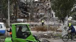 Communal workers clean the debris from the street in front of a heavily damaged building after a Russian attack in Sloviansk, Ukraine. 