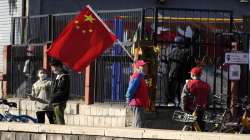 Residents and neighborhood watch members stand near a Chinese flag along a street ahead of the closing ceremony of the 20th National Congress of China's ruling Communist Party in Beijing, Saturday, Oct. 22, 2022. 