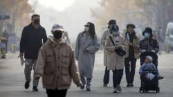 People wearing face masks walk along a pedestrian shopping street in the Wangfujing shopping district in Beijing. 