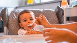 Mother feeding kid with a spoon.