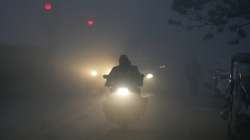 Vehicles ply on a road amid low visibility due to a thick layer of fog on a cold winter morning, in New Delhi.