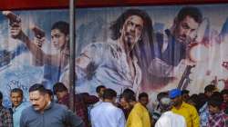 Police personnel sit outside a theatre on the first day show of the Bolllwood movie Pathaan, in Karad.