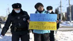 Police detain a demonstrator with a poster which reads "The war with Ukraine is a shame and a crime" during an action against Russia's attack on Ukraine in Omsk.