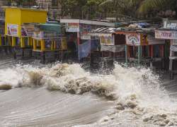 High waves crash against shops near the shore ahead of the landfall of Cyclone Biparjoy, in Mumbai