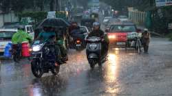 Commuters on a road amid rainfall, in Dehradun