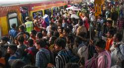 Security personnel attempt to control passengers rushing to board a train to travel home for the Chhath Puja festival, at New Delhi Railway Station