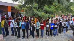 People stand in queue at a polling booth to cast vote during Rajasthan Assembly elections, in Jaipur.