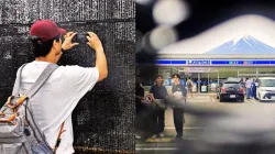 A visitor tries to take a photo through a hole in a black screen installed across from a convenience store in Fujikawaguchiko town