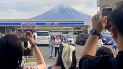 Visitors take a photo in front of a convenient store at Fujikawaguchiko town, Yamanashi prefecture, 