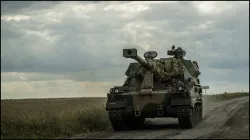 Ukrainian servicemen ride a self-propelled howitzer near the Russian border.