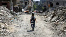 A Palestinian student walks between the rubble after attending a class in a tent set up on the rubbl