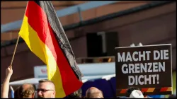 A person holds a poster reading: "Close the borders" during an Alternative for Germany (AfD) party protest.