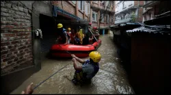 Security force members use an inflatable raft to bring residents to safety from a flooded area in Nepal