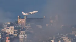 A Lebanese Middle East Airlines (MEA) plane takes off from Beirut-Rafic Hariri International Airport, as smoke rises over Beirut's southern suburbs after Israeli air strikes