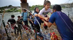 Migrants from Venezuela make their way through the razor wire after crossing the Rio Grande into the