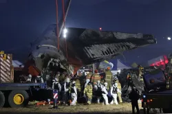 Firefighters and rescue team members work near the wreckage of a passenger plane at Muan Internation