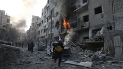 This photo, provided by the Syrian Civil Defence White Helmets, shows a Syrian White Helmet civil defense worker running in a destroyed neighborhood after the Syrian government forces hit Idlib city, Syria.