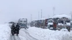 People walk past stranded vehicles on the Jammu-Srinagar National Highway during heavy snowfall, at Qazigund in Anantnag district of South Kashmir.