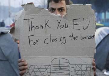 A refguee holds message, “Thank you EU for closing the border” during a protest