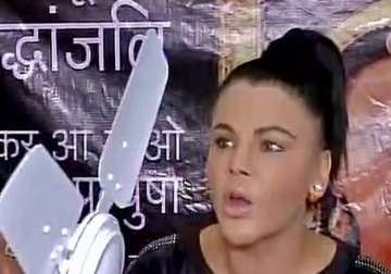 Rakhi Sawant holding a ceiling fan at a press conference 