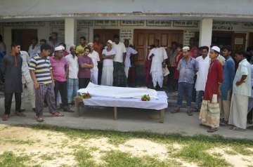 Locals surround body of a Hindu ashram worker who was hacked to death 